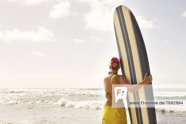 USA  Hawaii  Milde erwachsene Frau stehend mit Surfbrett am Strand