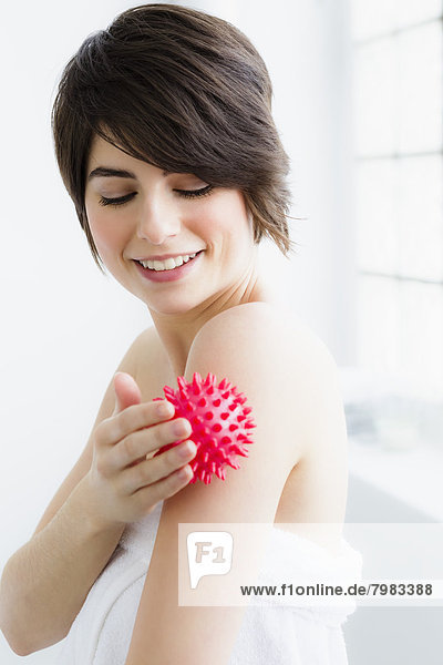 Junge Frau massiert mit Massageball  lächelnd