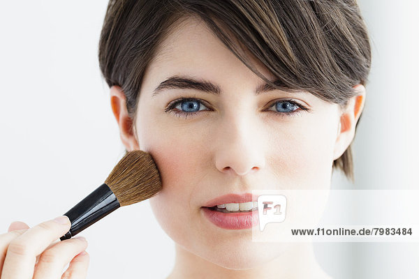 Young woman using blusher brush  close up