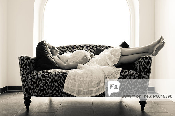 Schwangere Frau liegt auf dem Sofa
