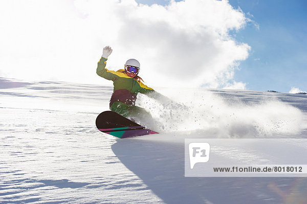 Junge Frau beim Snowboarden