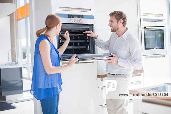 Young couple looking at oven in kitchen showroom