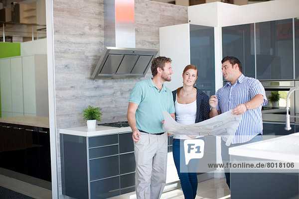 Young couple with salesman in kitchen showroom