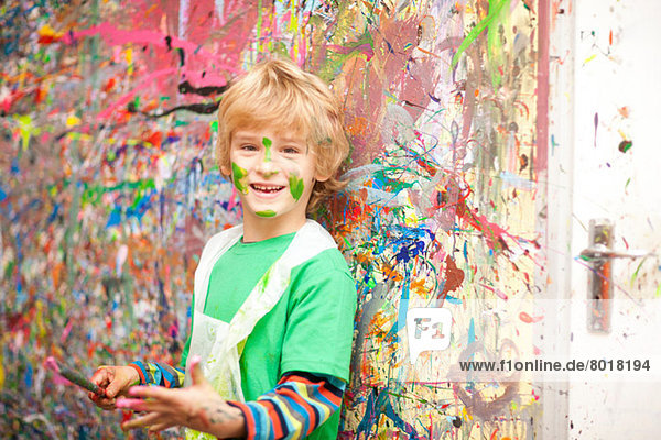 Boy in front of paint-splattered wall