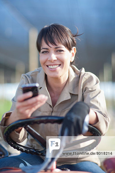 Frau im Fahrzeug mit Handy in der Gärtnerei