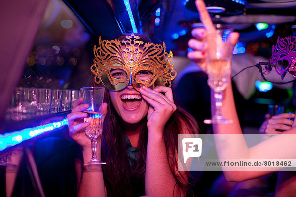 Young woman wearing mask with wine glass in limousine