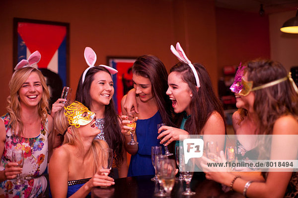 Junge Frauen lachen mit Getränken auf der Hühnerfeier