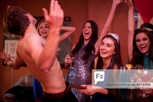 Young women watching male stripper at hen party