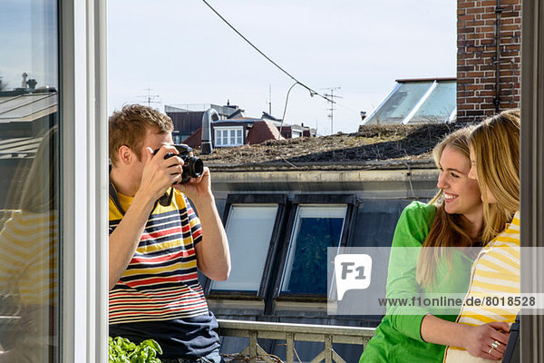 Junger Mann fotografiert Frauen auf dem Dach