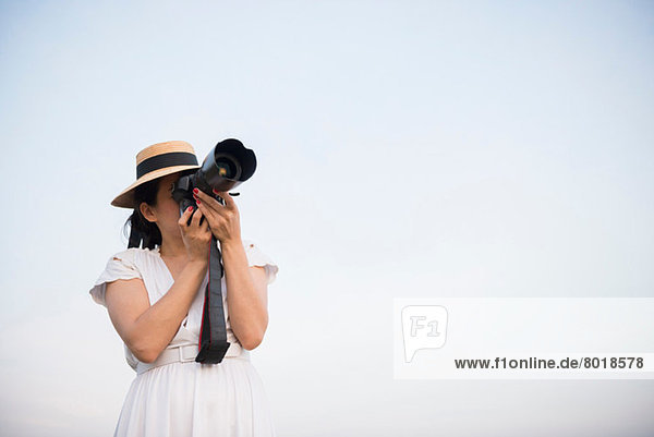 Woman taking photograph against clear sky