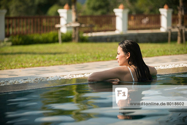 Woman leaning on edge of swimming pool