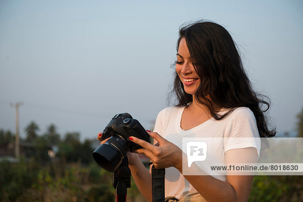 Frau mit langen schwarzen Haaren hält Kamera