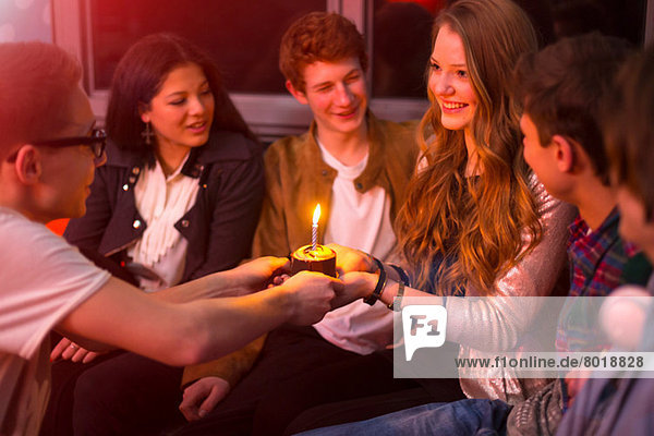 Gruppe von Teenagern  die um den Geburtstagskuchen sitzen