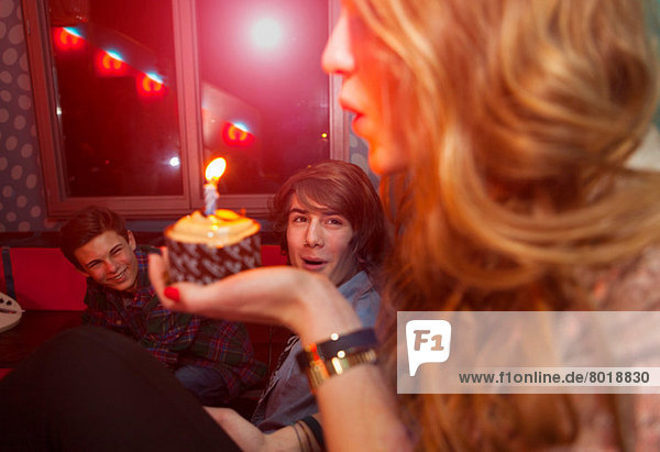 Teenagermädchen bläst Kerze auf Geburtstagskuchen aus