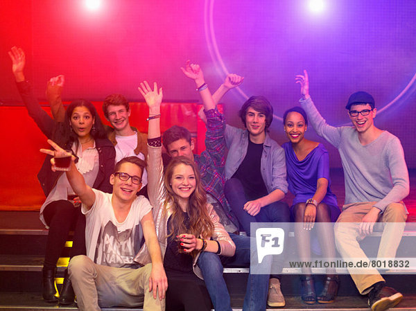 Gruppe von Teenagern und jungen Erwachsenen bei einer Party mit Getränken und erhobenen Armen