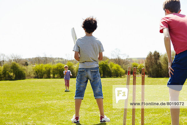 Jungs spielen Cricket auf dem Spielfeld