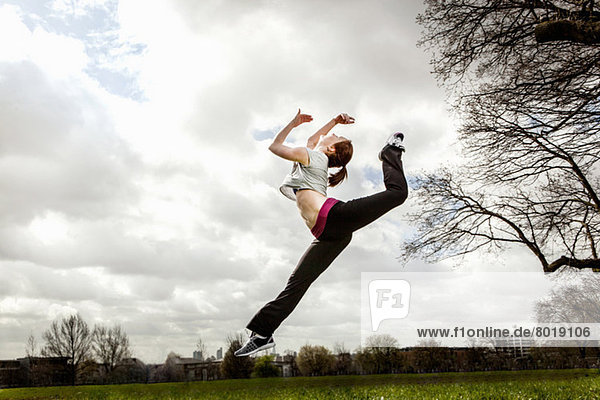 Frau springt in der Luft mit gebeugtem Bein
