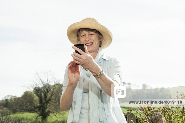 Seniorenfrau lächelt Nachricht auf dem Handy an