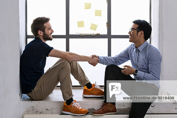 Two young male creatives shaking hands