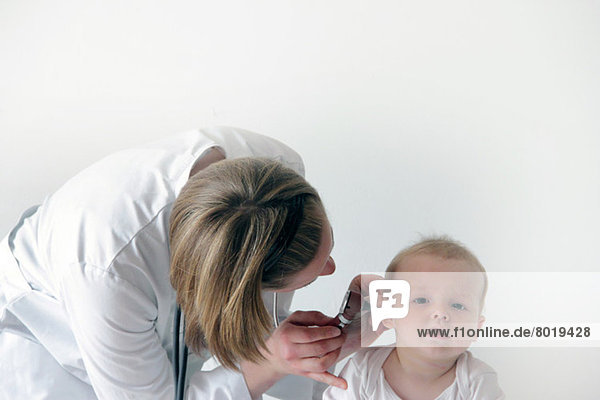 Ärztin untersucht das Ohr des Babys
