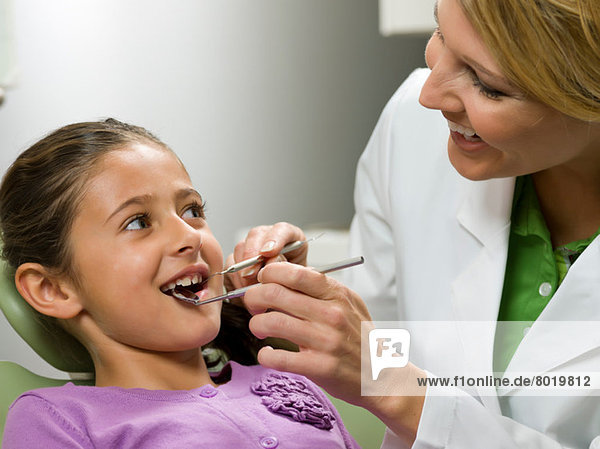 Dentist looking at young girl's teeth