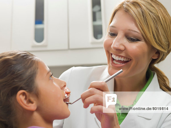 Dentist looking at young girl's teeth