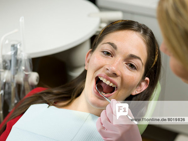 Dentist examining young woman's teeth