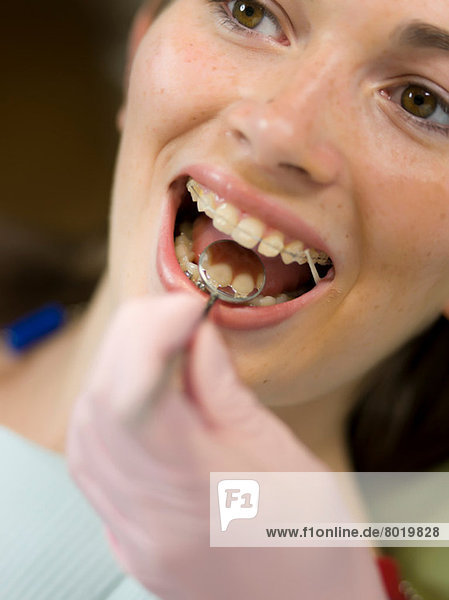 Dentist examining young woman's teeth  close up