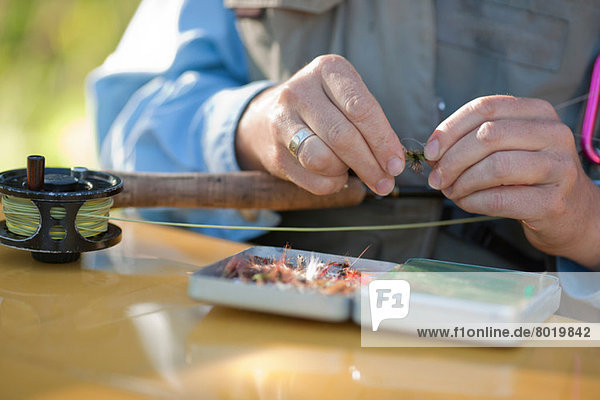 Mature woman preparing bait for fly fishing  close up