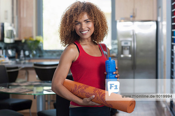 Mittlere erwachsene Frau mit Yogamatte und Wasserflasche  Portrait