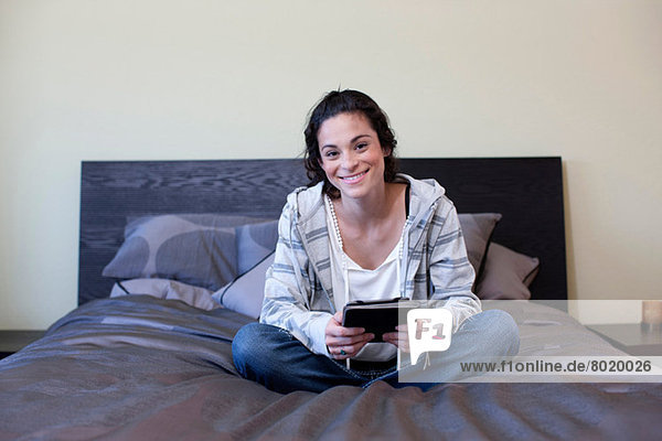 Young woman sitting bed with electronic book  portrait