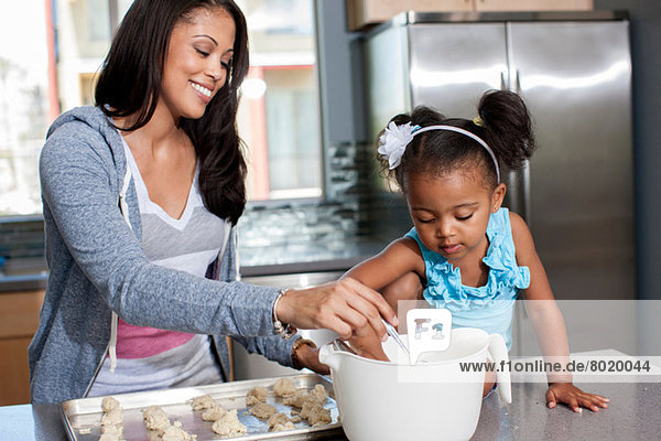 Mittlere erwachsene Frau beim Backen mit Tochter in der Küche