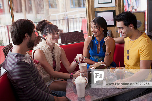 Four friends sitting together in diner  smiling