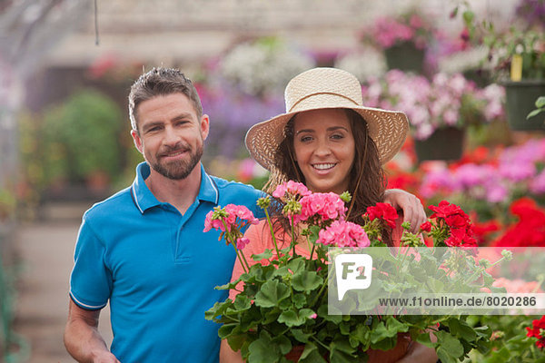 Mittelgroßer Mann und junge Frau mit Pflanzen im Gartencenter  Portrait