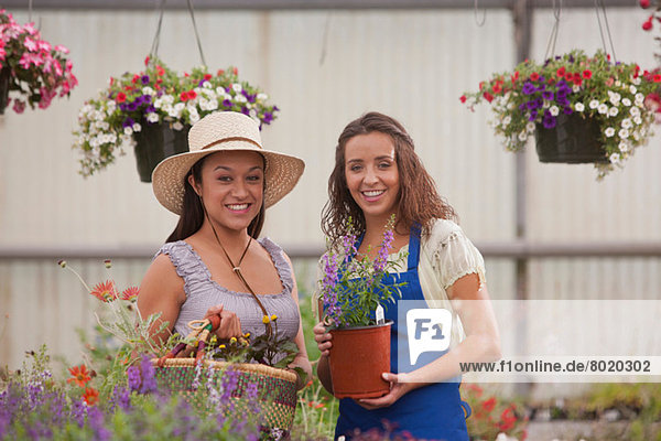 Junge Frauen mit Pflanzen im Gartencenter  lächelnd