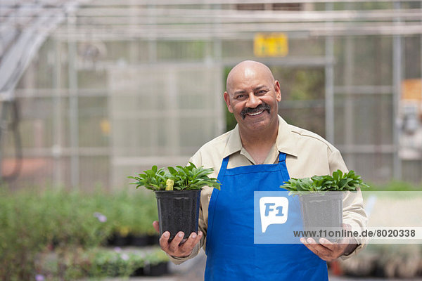 Reifer Mann mit Pflanzentöpfen im Gartencenter  Portrait