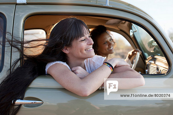Young women travelling in car on road trip  smiling