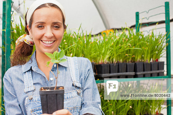 Young woman holding plant in garden centre  portrait