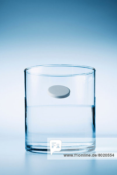 Tablette im Begriff  in ein Glas Wasser zu fallen.