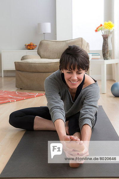 Mittlere erwachsene Frau beim Yoga zu Hause