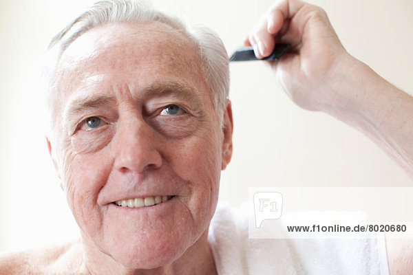 Senior Mann beim Kämmen der Haare