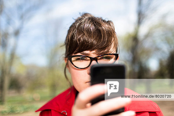 Frau im Stadtpark sucht Smartphone