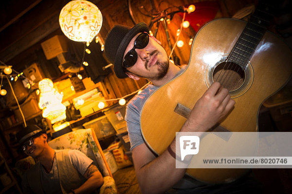 Mann mit Hut und Sonnenbrille beim Gitarrespielen