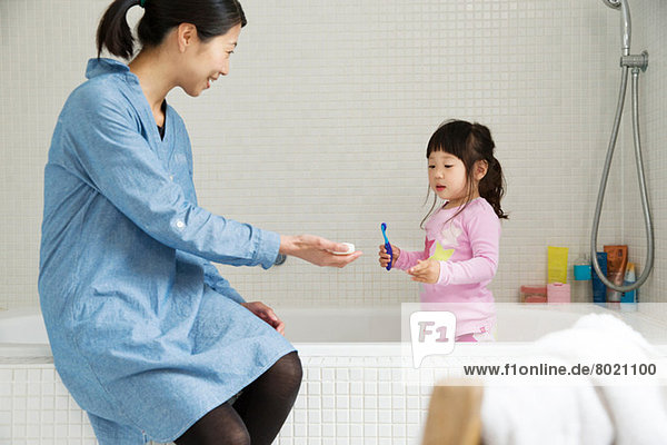 Mutter mit Kleinkind im Bad stehend mit Zahnbürste