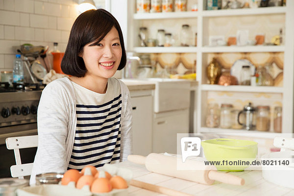 Porträt einer jungen Frau am Küchentisch mit Backzutaten