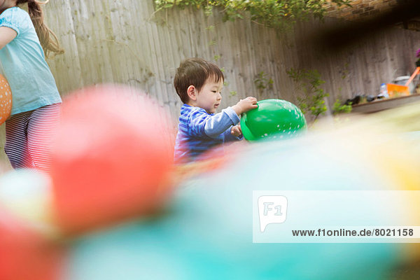 Männliches Kleinkind beim Spielen im Garten mit Ballon