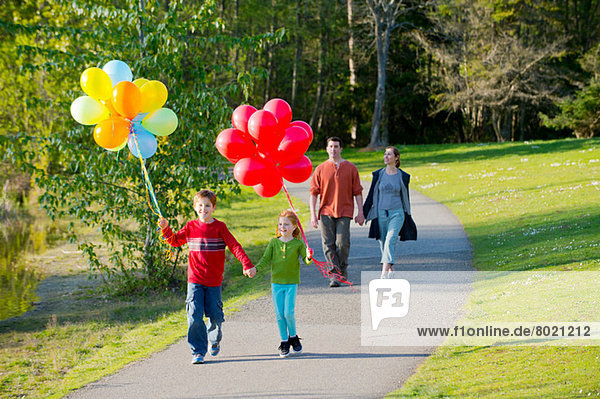 Familienwanderung durch den Park mit Luftballons