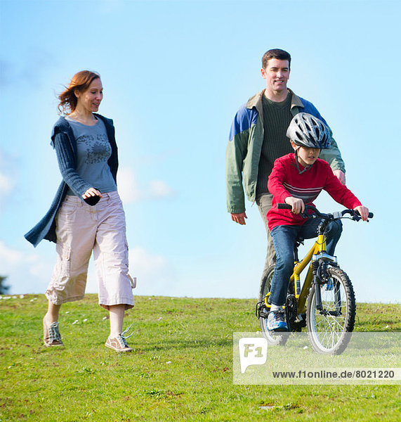 Parents watching son riding bicycle
