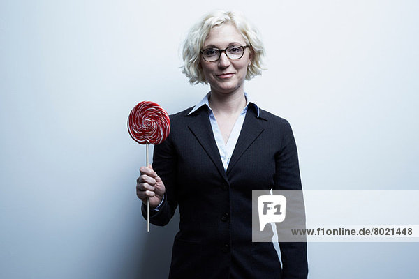 Studio-Porträt einer blonden Geschäftsfrau mit rotem Lolli