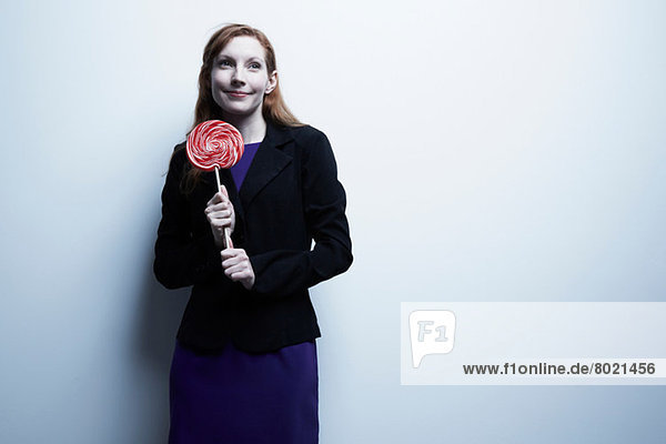 Studio-Porträt einer jungen Geschäftsfrau mit rotem Lolli